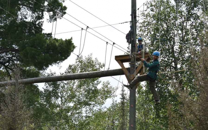 a student balances on ropes while participating in a high ropes course with outward bound